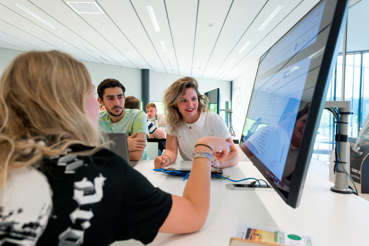 Studenten overleggen over een project met beeldscherm