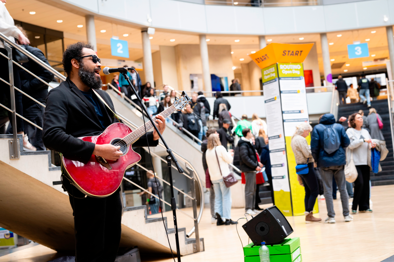 Gitarist maakt muziek in Atrium tijdens Open Dag