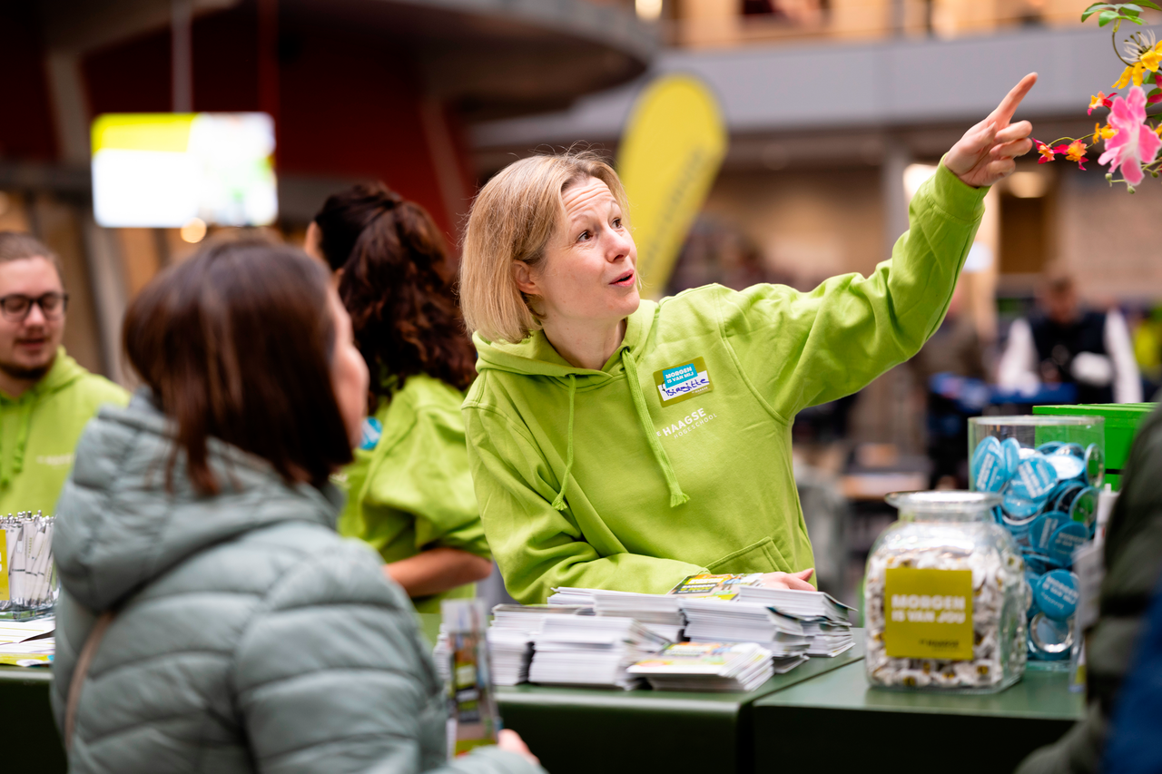 Medewerker Open Dag wijst een bezoeker de goede kant op