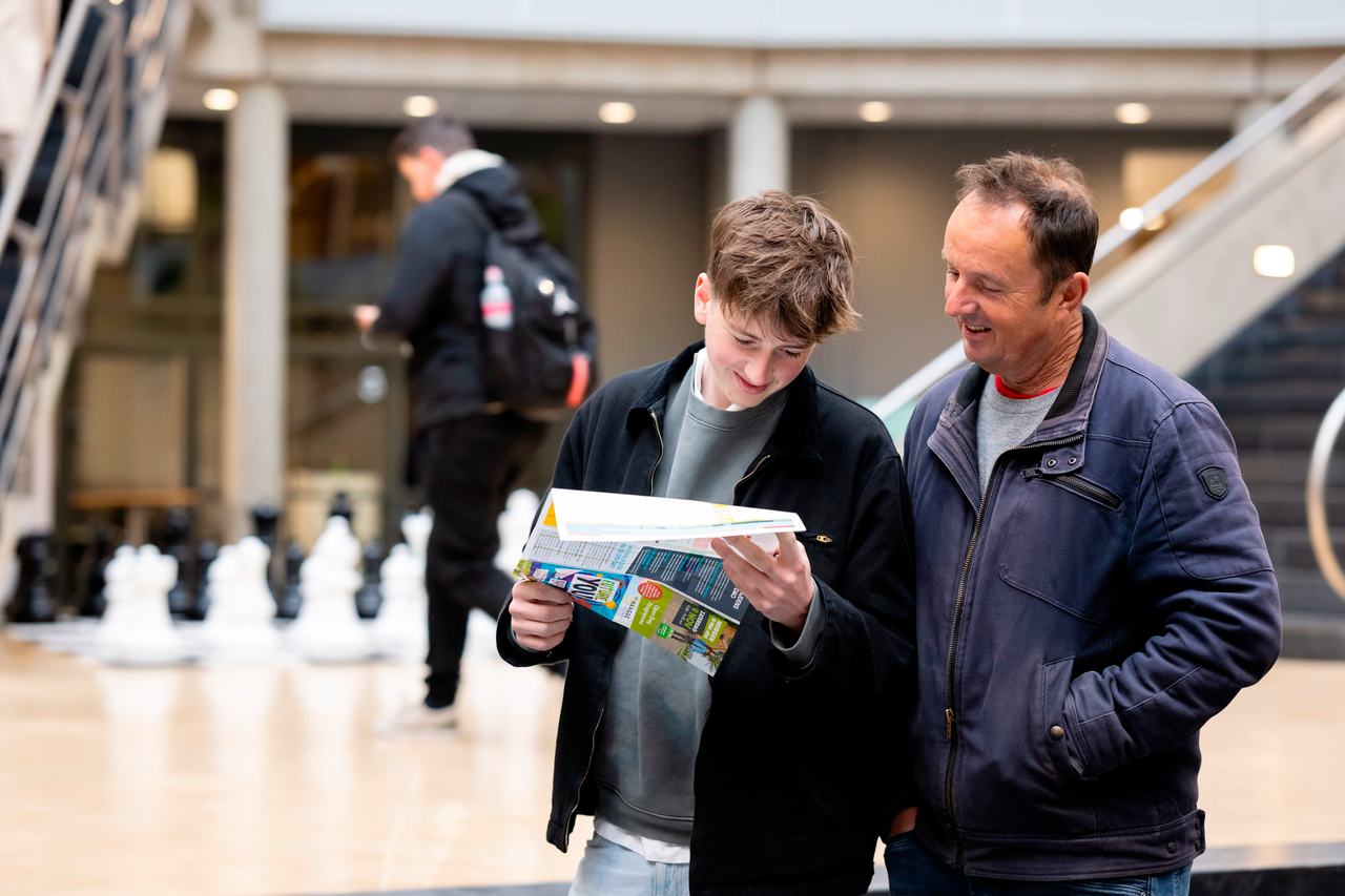 Vader en zoon kijken naar programma Open Dag