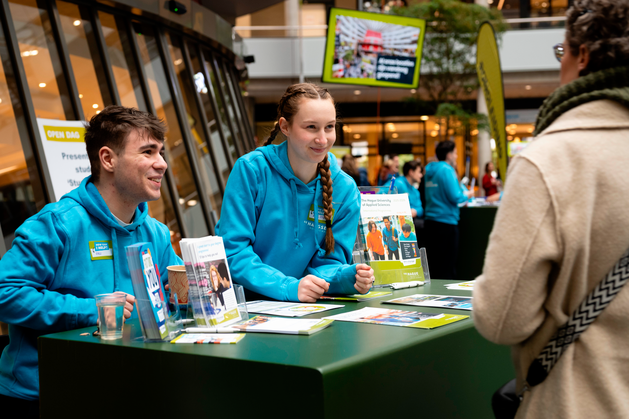 Twee studenten in blauwe trui achter welkomstbalie